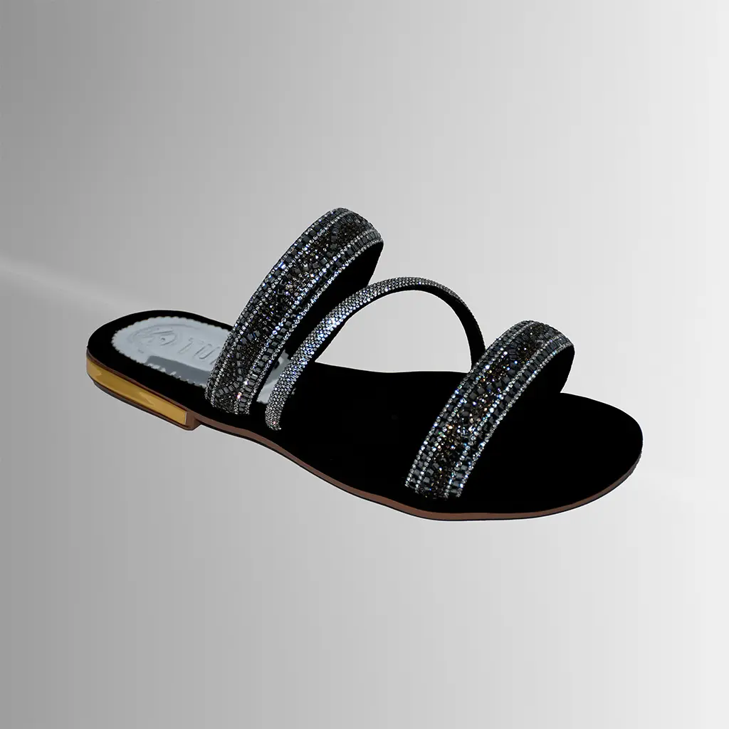 Una sandalia plana negra con brillo delicado, pensada para looks modernos y fáciles de combinar.